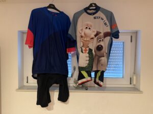 Chris’s cycling kit from ten years ago hanging beside one of his current Fat Lad At The Back outfits, comparing the jerseys and bib shorts.